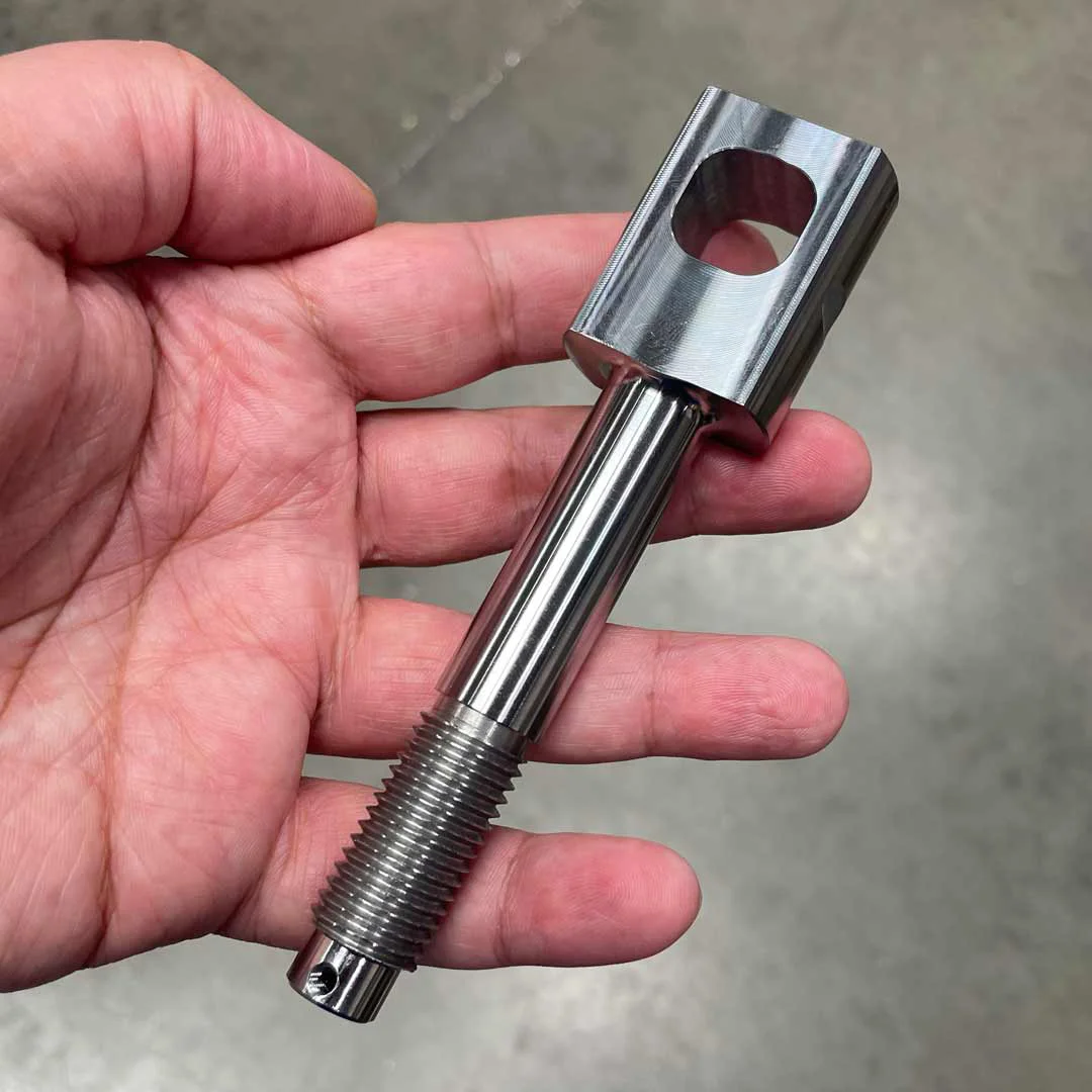 A precision turned part held by a team member at Genoa Tool.